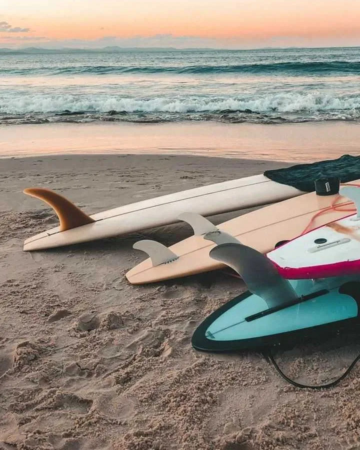 Pranchas de surf na areia de uma praia ao entardecer.
